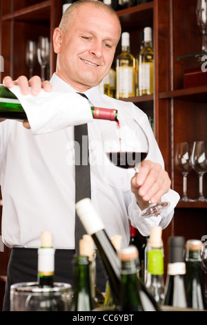 Presso il bar - cameriere versare il vino rosso in vetro ristorante Foto Stock