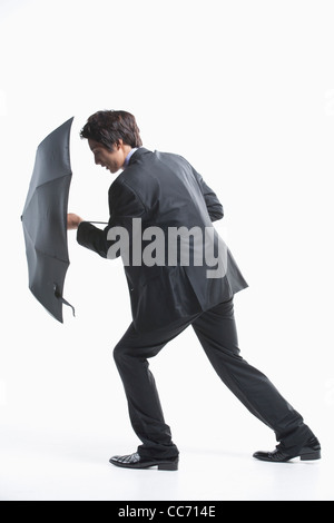 Un uomo che cerca di camminare in avanti con la difesa ombrello Foto Stock