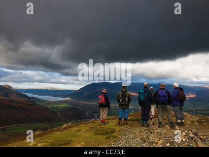 Un gruppo di vecchi walkers sorge sulla sommità di Barrow nel distretto del lago che guarda verso il lago Basingthwaite Foto Stock