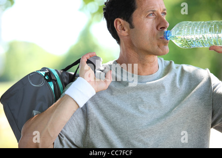 Athletic uomo maturo di bere acqua da una bottiglia Foto Stock