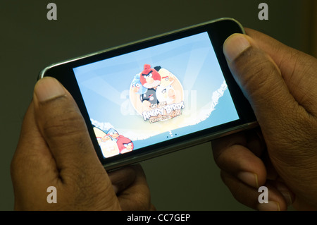 Mano che tiene l'iphone con angry birds schermata di gioco Foto Stock