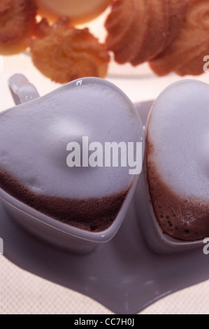 A forma di cuore ad un caffè espresso tazze cappuccino con assortimento di pasticceria sullo sfondo il giorno di san valentino trattare Foto Stock