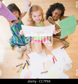 Bambini seduti sul pavimento afferrando i disegni Foto Stock