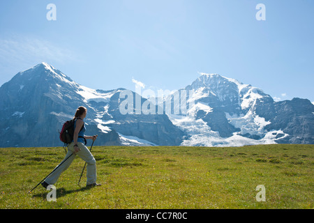 Woman Hiking utilizzando bastoni da passeggio, Oberland bernese, Svizzera Foto Stock