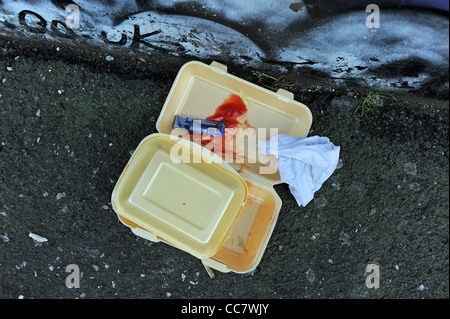 Il fast food contenitore gettato sul marciapiede con salsa di pomodoro e tovagliolo di carta UK street Foto Stock