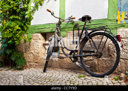 Rusty vecchia bicicletta in una strada a ciottoli del mezzo in legno case medievali nel Patrimonio Mondiale UNESCO città di Quedlinburg, Germania. Foto Stock