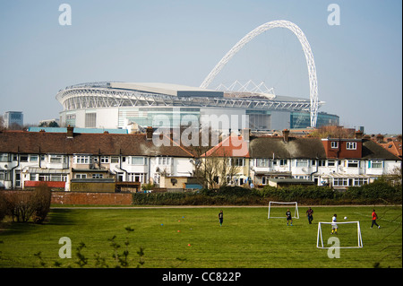 Lo stadio di Wembley visto da Brent River Park in London Borough of Brent con ragazzi che giocano a calcio davanti e case Foto Stock