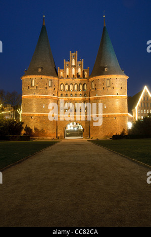 Holstentor illuminato o Holsten Gate nella serata con decorazioni di Natale, città anseatica di Lubecca, Germania Foto Stock