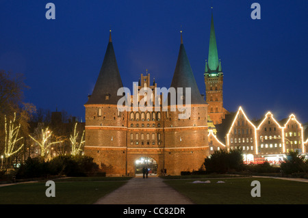 Holstentor illuminato o Holsten Gate nella serata con decorazioni di Natale, città anseatica di Lubecca, Germania Foto Stock