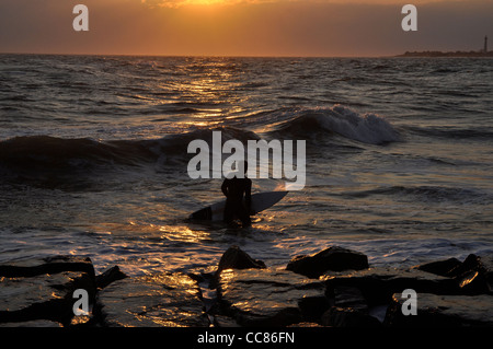 Surfer stagliano contro il sole di setting in Cape May New Jersey Foto Stock