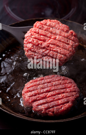 Due polpette di carne di manzo in una padella di ferro Foto Stock