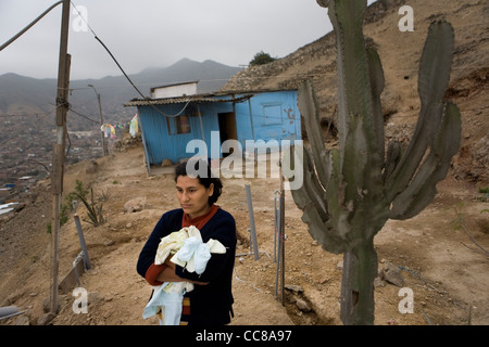 Una donna che sta al di fuori della propria casa in un villaggio squatter in Lima, Perù, Sud America. Foto Stock