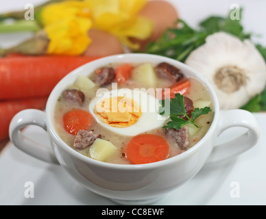 Tradizionale polacco borscht bianco con uova e salsiccia in bianco stoviglie per la pasqua Foto Stock