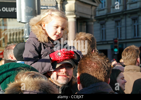 Bambina sul suo padre sulle spalle freddo soleggiata giornata di gennaio per avere un assaggio della Regina Margrethe II in oro pullman di stato Foto Stock