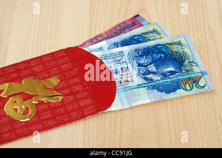 Dollaro di Hong Kong di valuta in contanti in un rosso e oro busta regalo tradizionalmente data in Cina al nuovo anno o per matrimoni Foto Stock