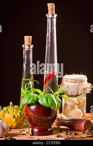 Bottiglia con olio vegetale e spezie fresche in scaffale di legno Foto Stock