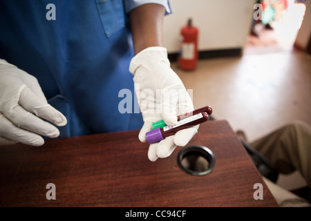 Un lavoratore di laboratorio contiene i campioni di sangue in una clinica a Kitwe, Zambia, Sud Africa. Foto Stock