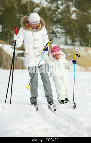 Bambina e sua madre lo sci in posizione di parcheggio Foto Stock