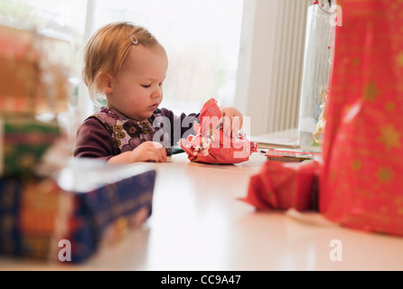 Baby girl guardando avvolto regalo di Natale Foto Stock