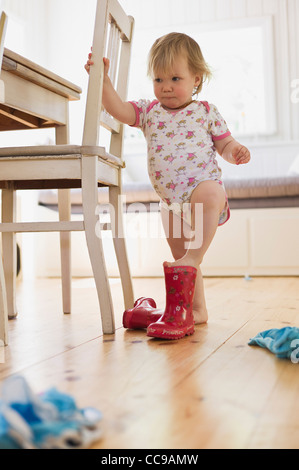 Ragazza mettendo in stivali di gomma Foto Stock