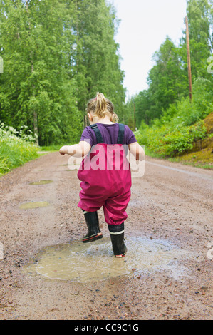 Giovane ragazza che gioca in una pozza, Svezia Foto Stock