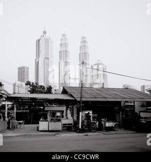 Il tramonto e la notte scende come le Torri Petronas incombono su di Kampung Baru nella città di Kuala Lumpur in Malesia in Estremo Oriente Asia sud-orientale. Città Travel Foto Stock