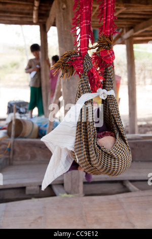 Bambino dorme nella swing in ombra del shanty house. Casa in paese, stato Shan, Birmania. Foto Stock