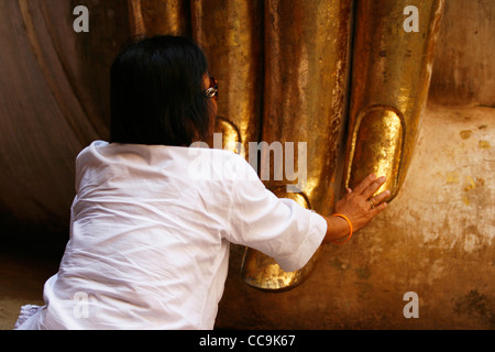 Una donna di rendere omaggio a Buddha all'interno di un tempio di Sukhothai Historical Park, Thailandia. Foto Stock