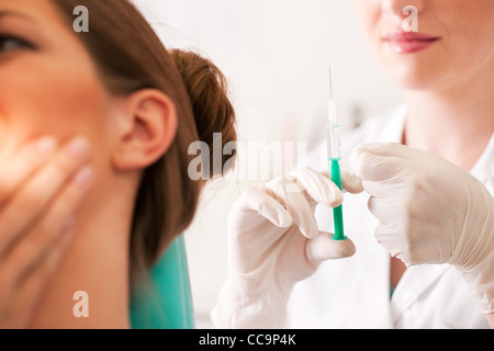 Presso il dentista - un paziente di sesso femminile è sempre pronto a ricevere una siringa anesteticazione (focus sulla siringa) Foto Stock