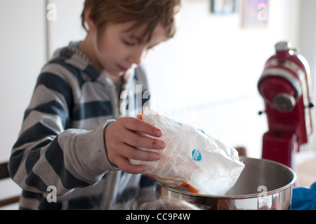 Ragazzo in cucina la cottura di una torta al cioccolato Foto Stock