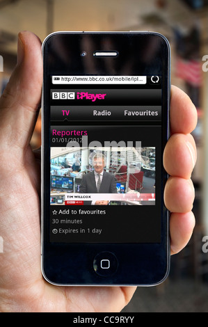 Guardando le notizie di BBC canale della BBC iPlayer su un Apple iPhone 4 allo smartphone tramite un hotspot Wi-Fi pubblico Foto Stock