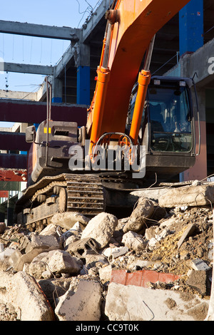 Un escavatore siede sui rifiuti da un sito di demolizione a Tours in Francia. Foto Stock