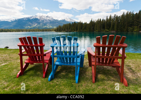 Tre sedie adirondack sul prato di fronte Lac Beauvert presso il Fairmont Jasper Park Lodge, Alberta, Canada. Foto Stock