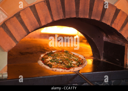 Lo chef rimuovendo un cinghiale pizza dal forno a legna, Cecco Ristorante, Solvang, Santa Ynez Valley, California Foto Stock