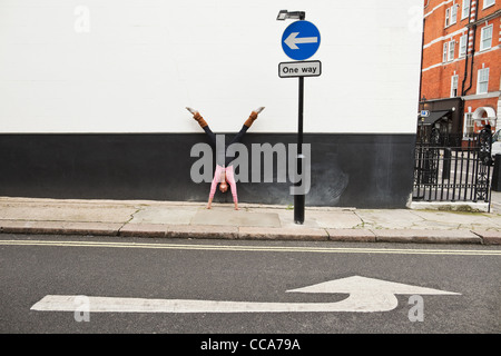 Donna di eseguire handstand sul marciapiede Foto Stock