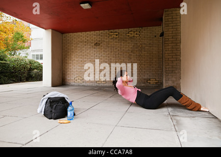 Donna in gamba scaldabiberon eseguendo sit ups Foto Stock