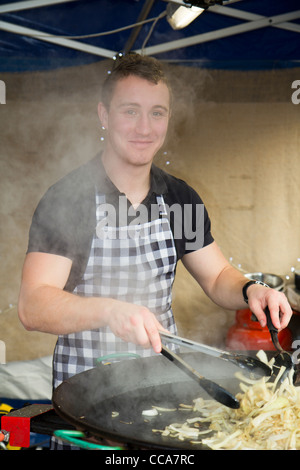 Uomo di agitazione e la cottura di cipolle sul cibo stallo a Chatsworth mercatino di Natale Derbyshire Inghilterra Foto Stock