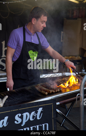 Uomo di grande cucina salsicce a Chatsworth mercatino di Natale Derbyshire Inghilterra Foto Stock