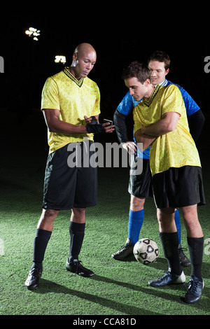 I giocatori di calcio guardando il cellulare del passo Foto Stock