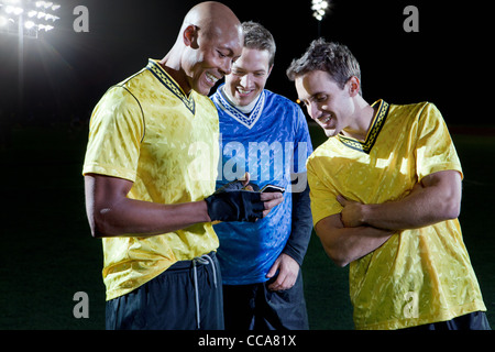 I giocatori di calcio guardando il cellulare del passo Foto Stock