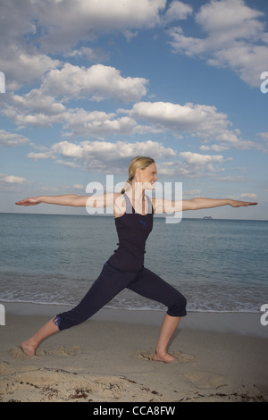 Metà donna adulta yoga in posa sulla spiaggia Foto Stock