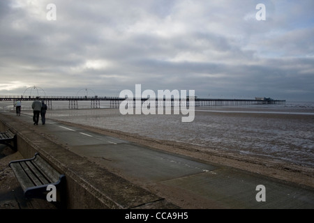 Un paio di un uomo e di una donna a camminare sulla spiaggia di Southport Lancashire Inghilterra con un uomo su una bici davanti. Foto Stock