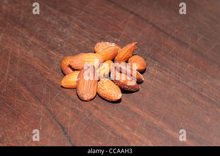 Salate mandorle intere su una tavola di legno Foto Stock