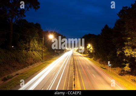 Macchine passando su un parkway al crepuscolo Foto Stock