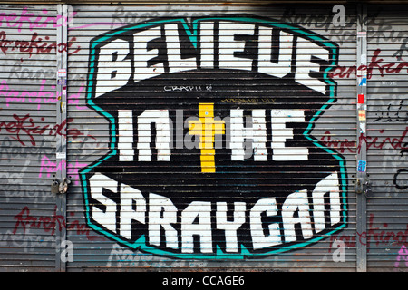 Credo nell'Spraycan graffiti su un Shoreditch shop otturatore Foto Stock