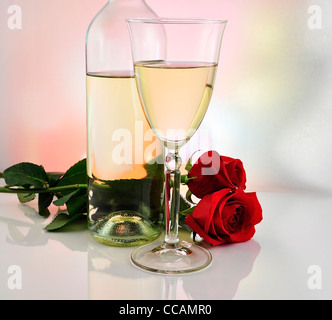 Un bicchiere di vino bianco con bottiglia e le rose Foto Stock