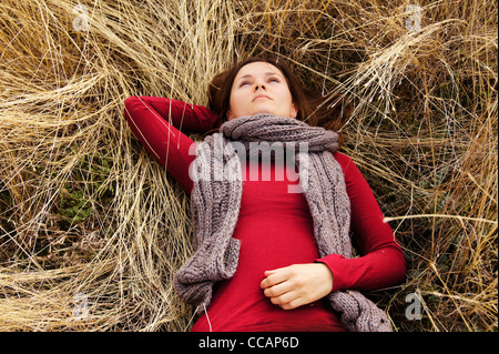 Giovane e bella ragazza distesa nella lunga dorata erba guardando il cielo Foto Stock