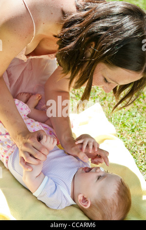 Madre dà la protezione solare per baby Foto Stock