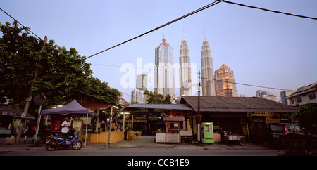 Il tramonto e la notte scende come le Torri Petronas incombono su di Kampung Baru nella città di Kuala Lumpur in Malesia in Estremo Oriente Asia sud-orientale. Città Travel Foto Stock