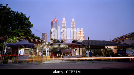 Il tramonto e la notte scende come le Torri Petronas incombono su di Kampung Baru nella città di Kuala Lumpur in Malesia in Estremo Oriente Asia sud-orientale. Città Travel Foto Stock